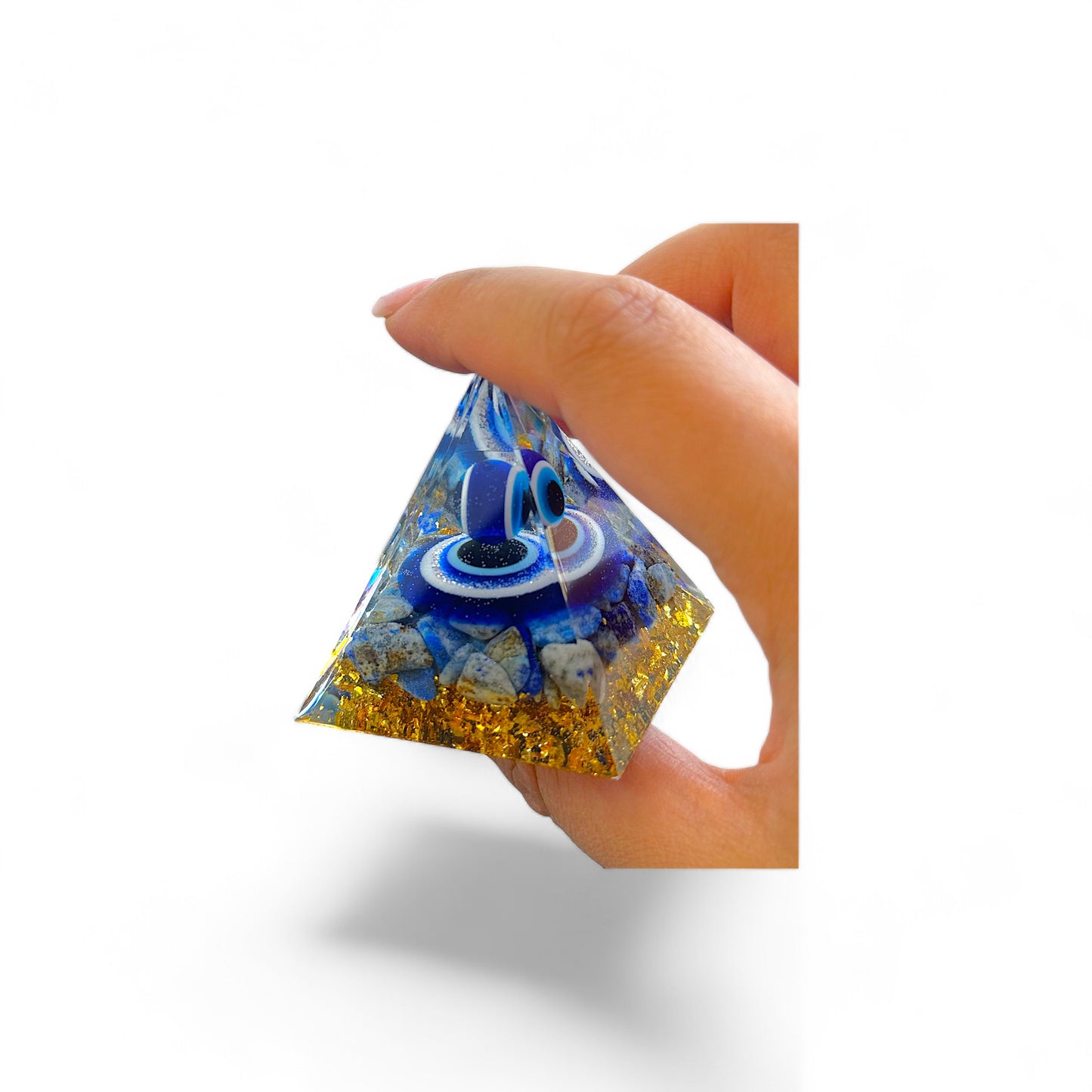 Persoon houdt een boze oog piramide van 5 cm vast, versierd met gouden kristallen