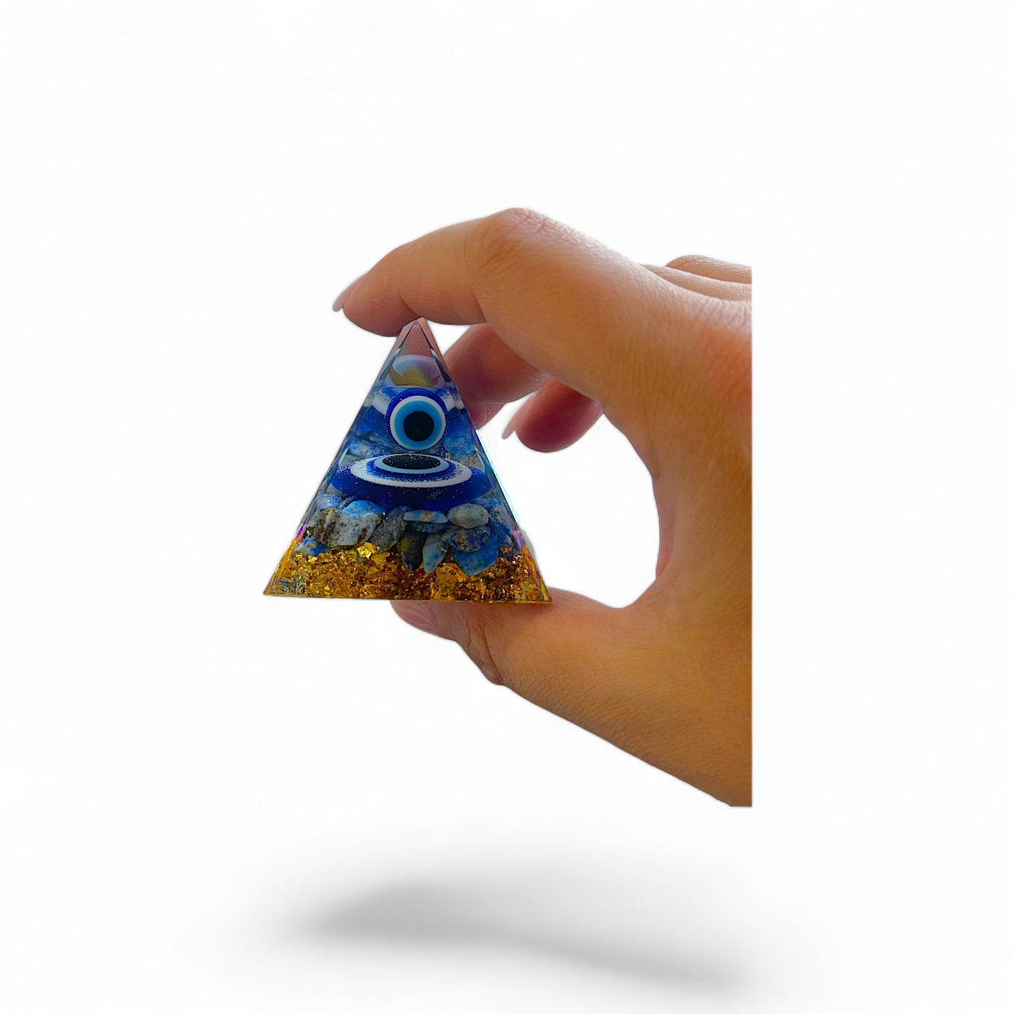 Boze oog piramide van Lapis steen met gouden kristallen, gehouden in de hand voor schaalvergelijking