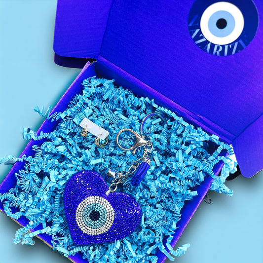 Boze Oog Cadeaubox 'Heartbeat' met donkerblauwe Nazar Heart sleutelhanger en gouden Nazar Mighty oorbellen. Een stijlvolle geschenkset die liefde en bescherming biedt, perfect voor een glamoureuze verrassing.